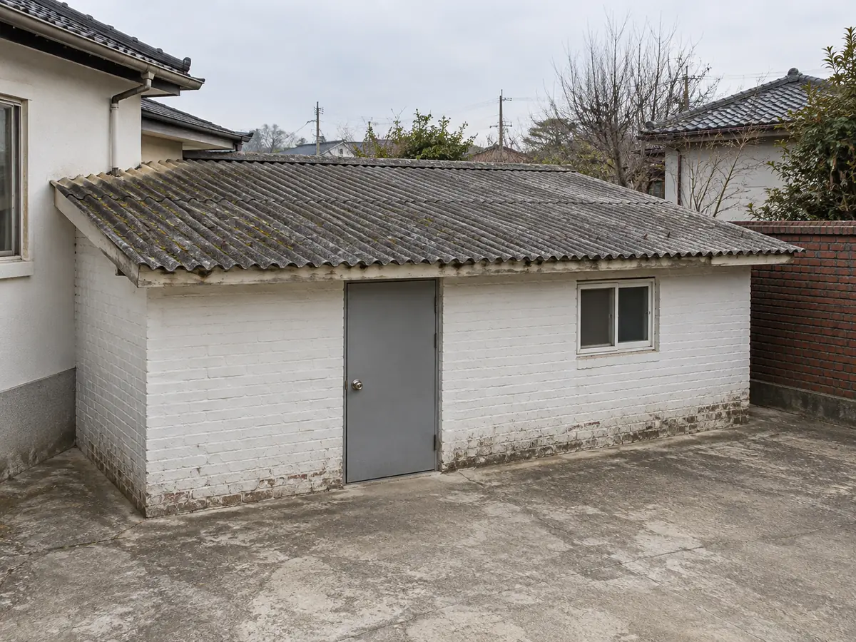 수원 석면 작업 장면 — 물결 모양 회색 지붕재가 얹힌 마당 창고