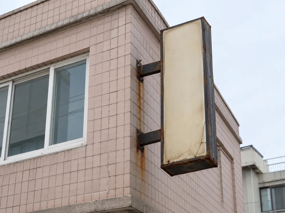 수원 간판 작업 장면 — 녹슨 고정대에 달린 낡은 돌출 간판 상자